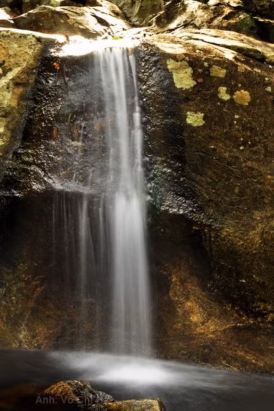 Suối đá nhấp nhô, nước chảy qua các gộp đá tạo âm thanh ầm ào.