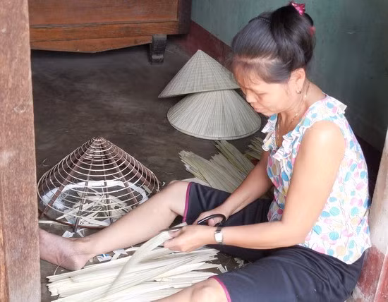 Một người làm nón ở thôn Hòa Dõng, xã Cát Tân đang cắt lá nón khô.