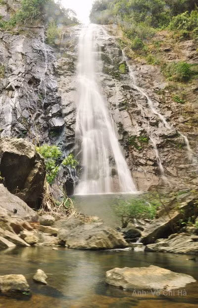 Vực đá dựng cao, nước từ dòng suối trên cao đổ xuống trông hùng vĩ.