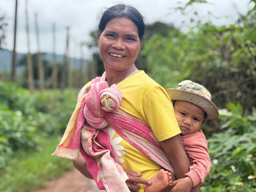 Một người mẹ địu con sau lưng bằng chiếc khăn vải cũ, nở nụ cười hiền lành với du khách. Ảnh: N.T.D nhung-nguoi-me-diu-con-sau-lung-bang-chiec-khan-vai-cu-buoc-chan-ran-roi-nu-cuoi-hien-lanh.jpg