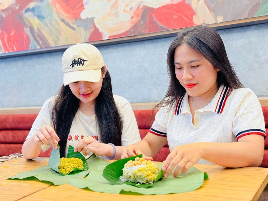 Chị Lê Thị Ni Na (bìa phải) gói xôi cốm cho khách hàng. Ảnh: M.K chi-na-ben-phai-anh-chon-loai-com-duoc-lam-tu-gao-nep-dac-biet-nhu-nep-thom-nep-tan-nep-quyt-nep-cai-hoa-vang-de-lam-xoi-comanh-mk.jpg