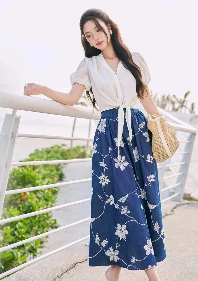Chân váy midi thêu hoa nổi gợi nhớ đến những thảm hoa nở rộ mùa hè. Dáng váy chữ A vừa che nhược điểm tốt vừa dễ dàng kết hợp cùng nhiều kiểu áo khác nhau, diện đi làm hay đi chơi đều khéo hòa hợp