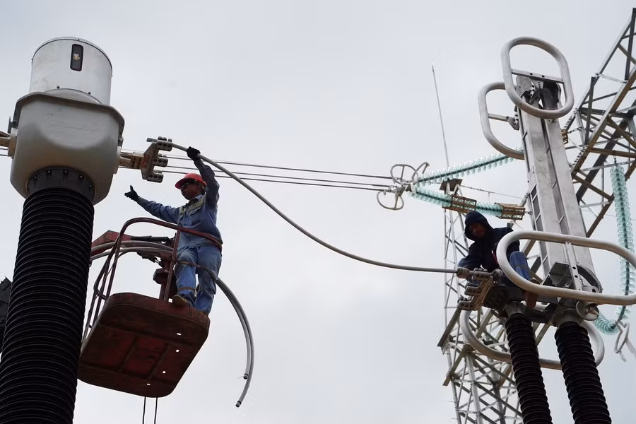 Công nhân cùng máy cẩu hối hả lắp đặt dây điện trên giàn sứ.