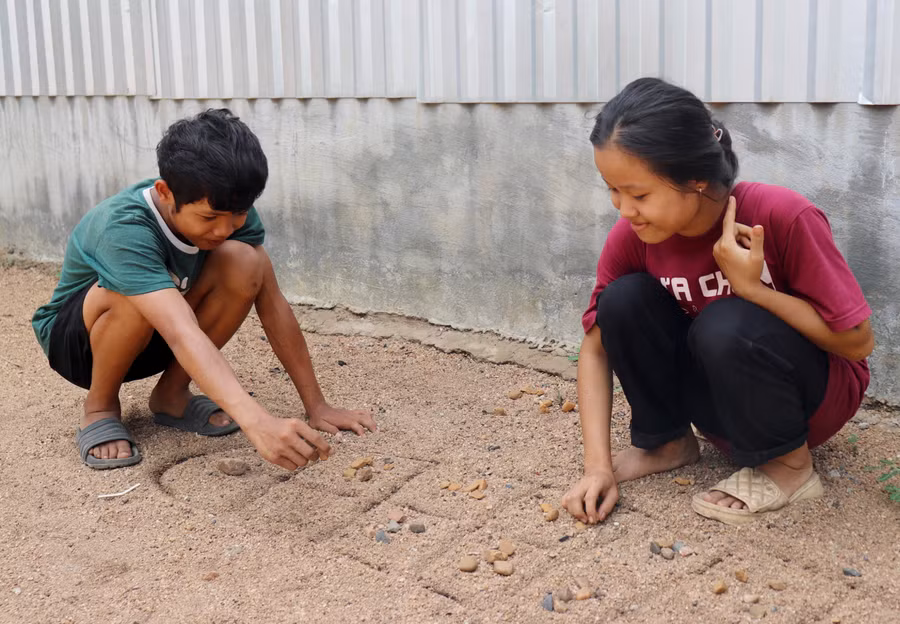 Rcom H' Nguyệt và Rcom Quân cùng nhau chơi trò ô ăn quan. Ảnh: Lạc Hà