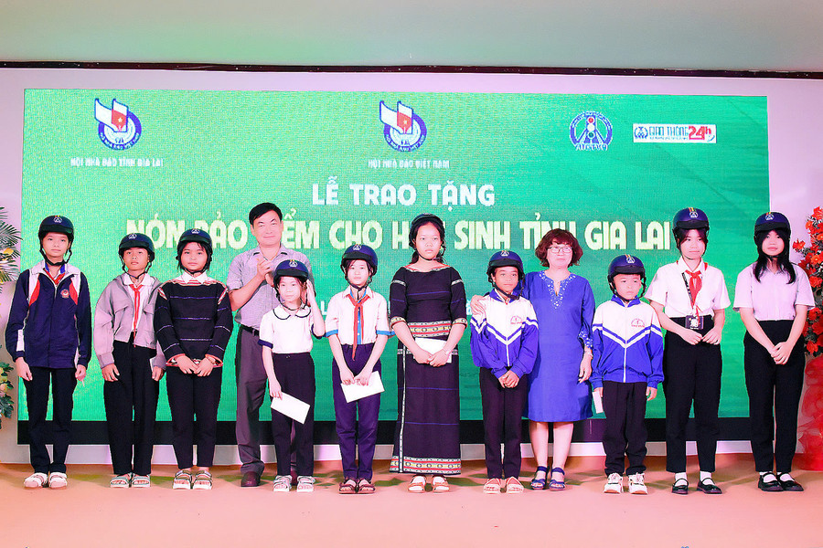 Ông Huỳnh Kiên-Tổng Biên tập Báo Gia Lai, Chủ tịch Hội Nhà báo tỉnh trao nón bảo hiểm Hội An toàn giao thông Việt Nam phía Nam cho các em học sinh nghèo của tỉnh Gia Lai. Ảnh: Đức Thuỵ