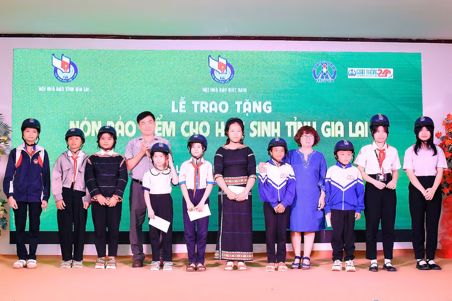 Ông Huỳnh Kiên-Tổng Biên tập Báo Gia Lai, Chủ tịch Hội Nhà báo tỉnh trao nón bảo hiểm Hội An toàn giao thông Việt Nam phía Nam cho các em học sinh nghèo của tỉnh Gia Lai. Ảnh: Đức Thuỵ