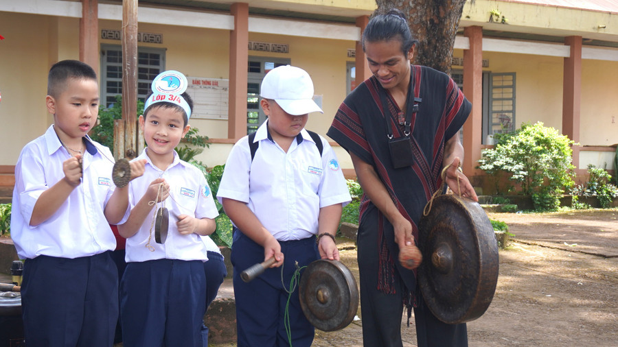 Học sinh say sưa trải nghiệm đánh chiêng, lắng nghe nghệ nhân kể chuyện về văn hoá cồng chiêng Tây Nguyên. Ảnh: Chu Hằng chieng.jpg