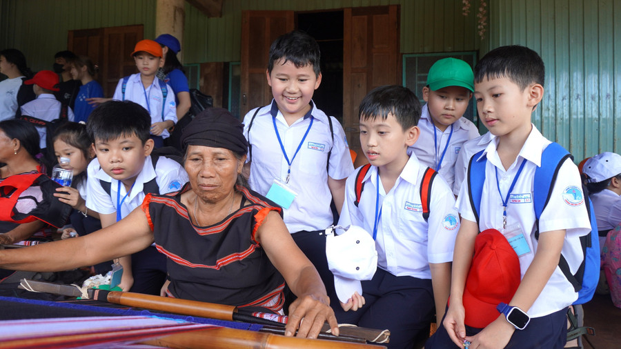 Nhiều học sinh thích thú khi được theo dõi các bà, các cô dệt vải thổ cẩm. Ảnh: Chu Hằng det-tho-cam.jpg
