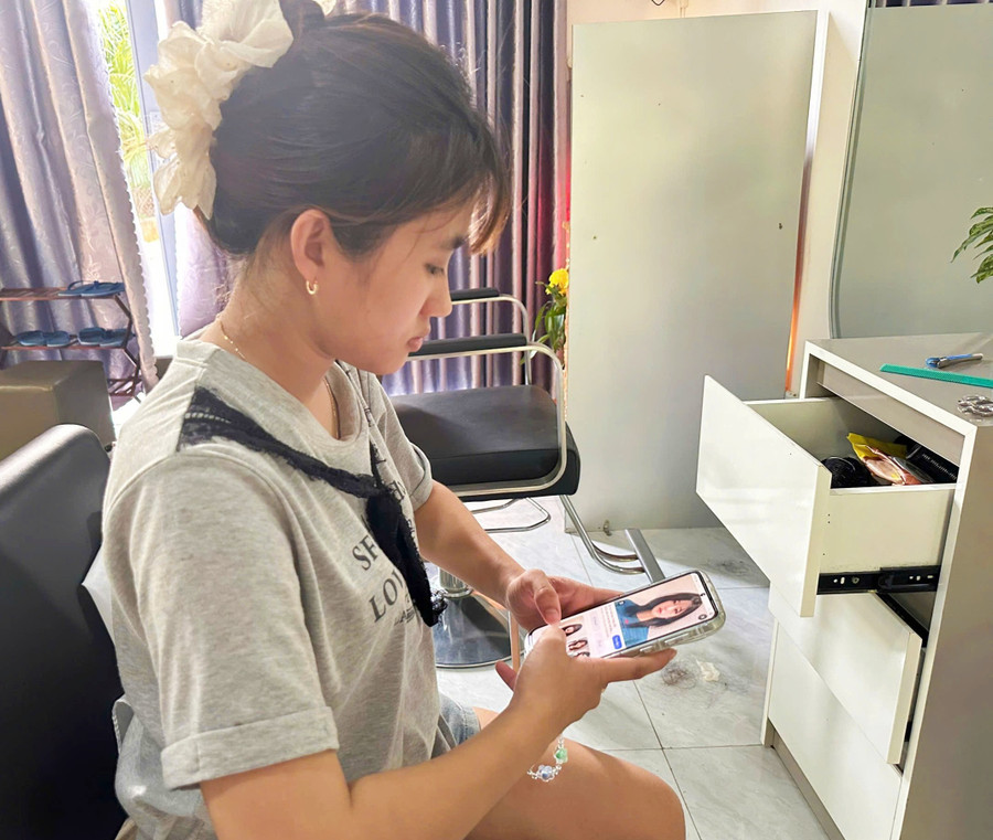 Bạn Nguyễn Thị Thanh Trúc tranh thủ xem tin tức để tìm các kiểu tóc mới nhằm cập nhật xu hướng. Ảnh: Đồng Lai img-20250805-171837.jpg