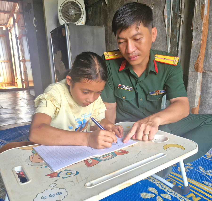 Cán bộ Công ty TNHH Một thành viên 72 hướng dẫn em Kpuih H’Lang học bài. Ảnh: Vĩnh Hoàng 1.jpg
