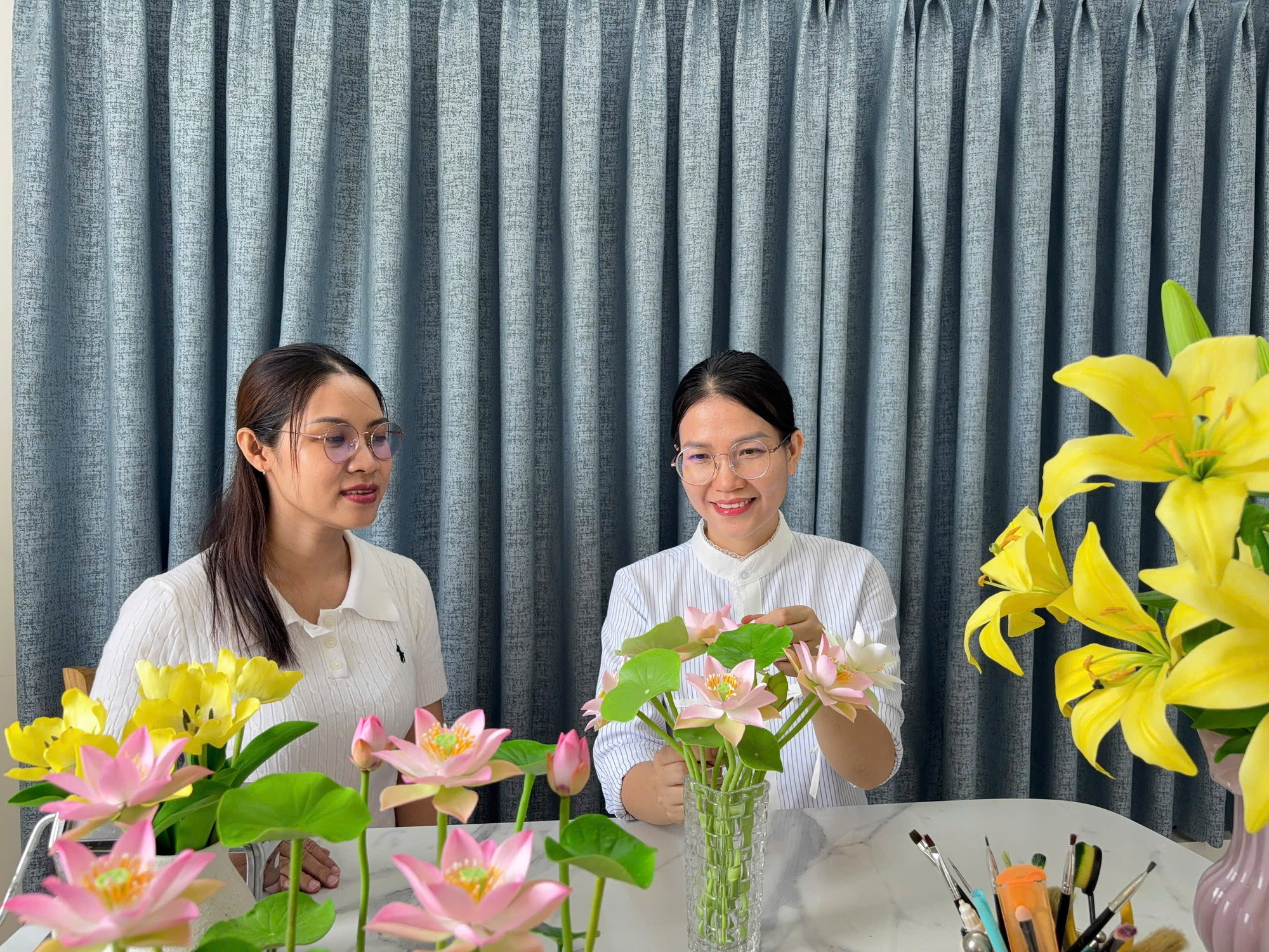 Chị Thảo (phải) giới thiệu một số mẫu hoa tự làm bằng đất sét. Ảnh: D.L handmade-chi-thao-2.jpg