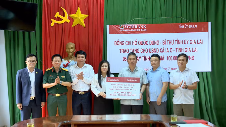 Phó Chánh văn phòng Tỉnh ủy Hoàng Thị Nguyệt Nga thừa ủy quyền của Bí thư Tỉnh ủy Hồ Quốc Dũng trao bảng tượng trưng tặng 5 bộ máy vi tính cho UBND xã Ia O. Ảnh: Huy Toàn