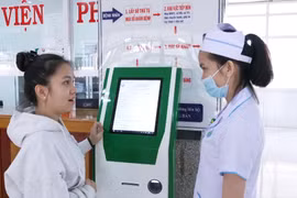 Nhân viên y tế Bệnh viện Nhi Gia Lai hướng dẫn người dân đăng ký khám chữa bệnh trên Kiosk y tế thông minh. Ảnh: HỒNG QUÝ