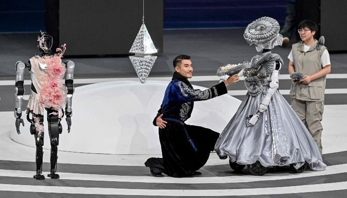 Người và robot cùng biểu diễn tại lễ khai mạc. Ảnh: AFP 618926-3994488-updates.jpg