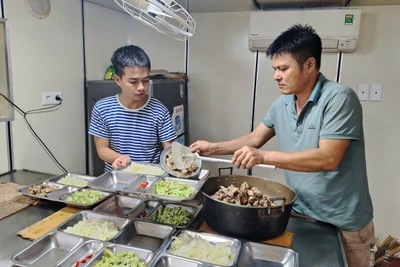 Thiếu tá Lê Đăng Huy (bìa phải)-Bếp trưởng Tổ phục vụ tàu Trường Sa 21 và Hạ sĩ Phạm Hồng Sơn chuẩn bị bữa cơm tối. Ảnh: Q.T