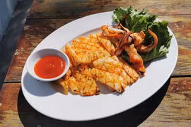 Mực một nắng nướng muối ớt. (Ảnh: Taste Atlas)