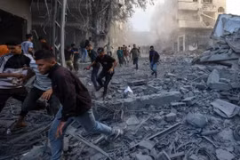 Người dân chạy trốn khi Israel không kích một tòa nhà ở trại Bureij, trung tâm Gaza vào ngày 19-10. Ảnh: Eyad Baba/AFP/Getty Images