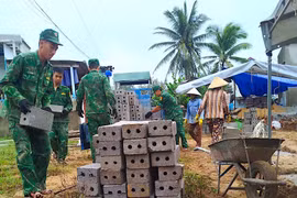 Cán bộ, chiến sĩ Đồn Biên phòng Tam Quan Nam hỗ trợ vận chuyển vật liệu xây nhà tình nghĩa cho gia đình thuyền viên Hà Quốc Phong. Ảnh: T.B
