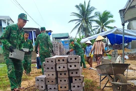 Cán bộ, chiến sĩ Đồn Biên phòng Tam Quan Nam hỗ trợ vận chuyển vật liệu xây nhà tình nghĩa cho gia đình thuyền viên Hà Quốc Phong. Ảnh: T.B