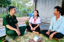 Thiếu tá Nguyễn Văn Luân (bìa trái) động viên em Nguyễn Thị Thảo Nguyên là "Con nuôi Đồn Biên phòng" cố gắng vượt khó học tập. Ảnh: P.D