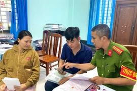 Cán bộ Công an phường An Nhơn Nam hướng dẫn, hỗ trợ người dân thực hiện thủ tục đăng ký thường trú cho con qua ứng dụng VNeID. Ảnh: Nguyễn Chơn