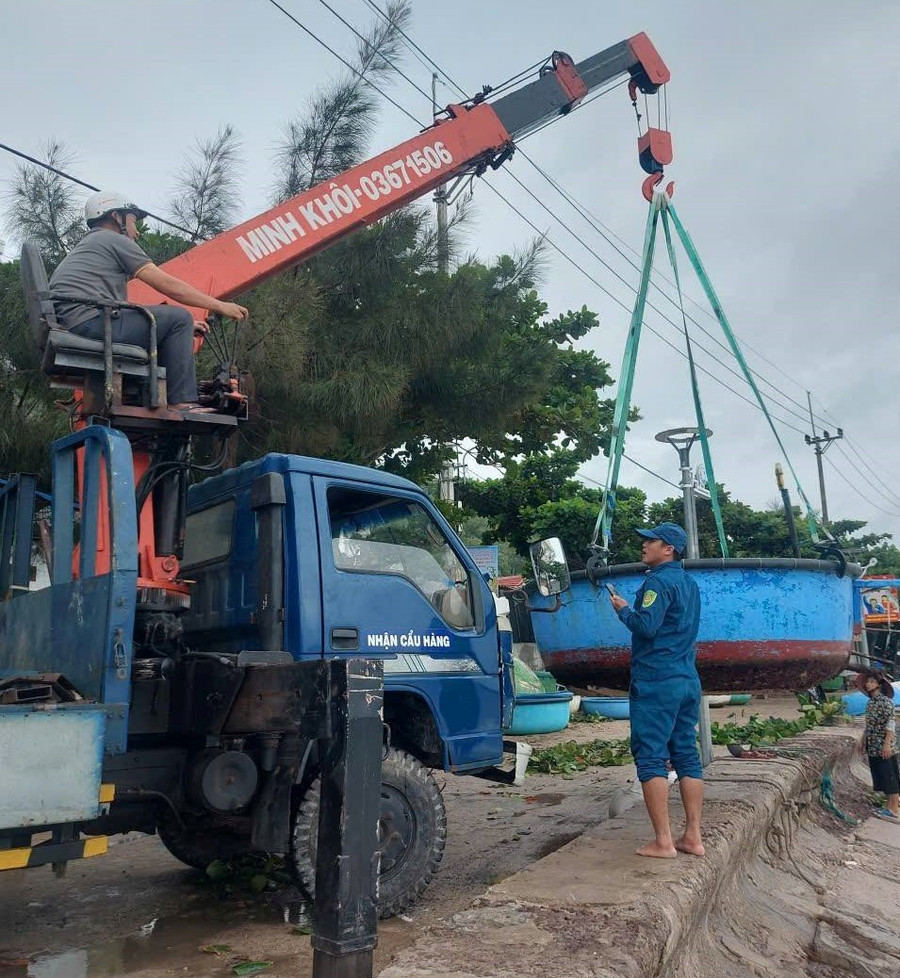 Chính quyền xã đảo Nhơn Châu hỗ trợ bà con đưa thúng máy lên bờ tránh bão số 12. Ảnh: ĐVCC tau-ca.jpg