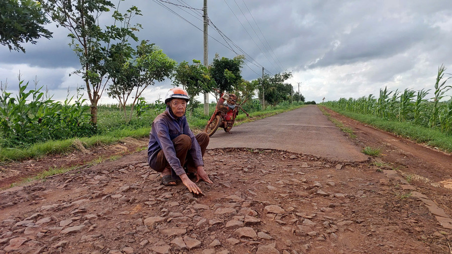 Ông Vũ Văn Con (thôn Đoàn Kết, xã Bờ Ngoong) bên đoạn đường bị bong tróc, trơ lớp đá dăm. Ảnh: Nguyễn Diệp z6944788640636-f8fe41b41c9aedfda17f7c14982af41f.jpg
