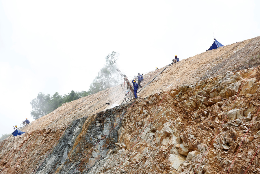 Công nhân thi công gia cố mái ta luy một khu vực có nguy cơ sạt lở trên tuyến đường tránh phía Nam thị trấn Phú Phong. Ảnh: H.P mg-6155.jpg