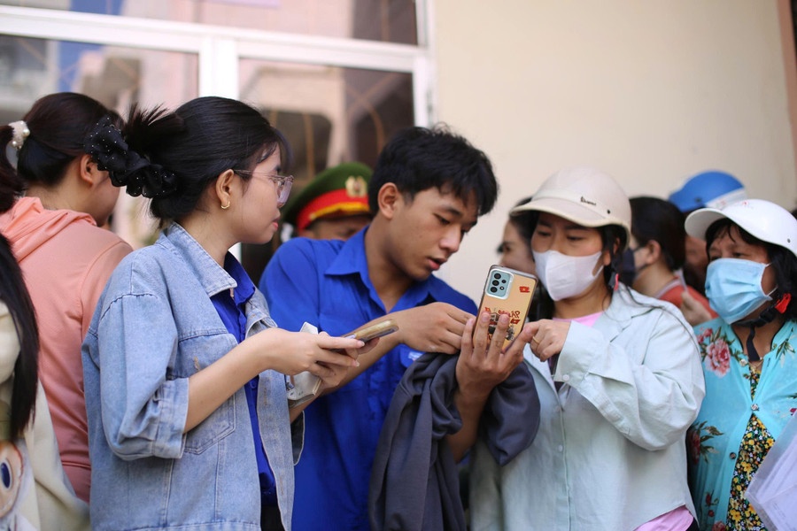 Đoàn viên thanh niên hỗ trợ người dân truy cập app VNeID trên điện thoại thông minh lấy thông tin cư trú toàn thể các thành viên trong gia đình để làm thủ tục nhận tiền. Ảnh: H.P z6963822609535-87571b9ec59043cd752a88d137426a75.jpg