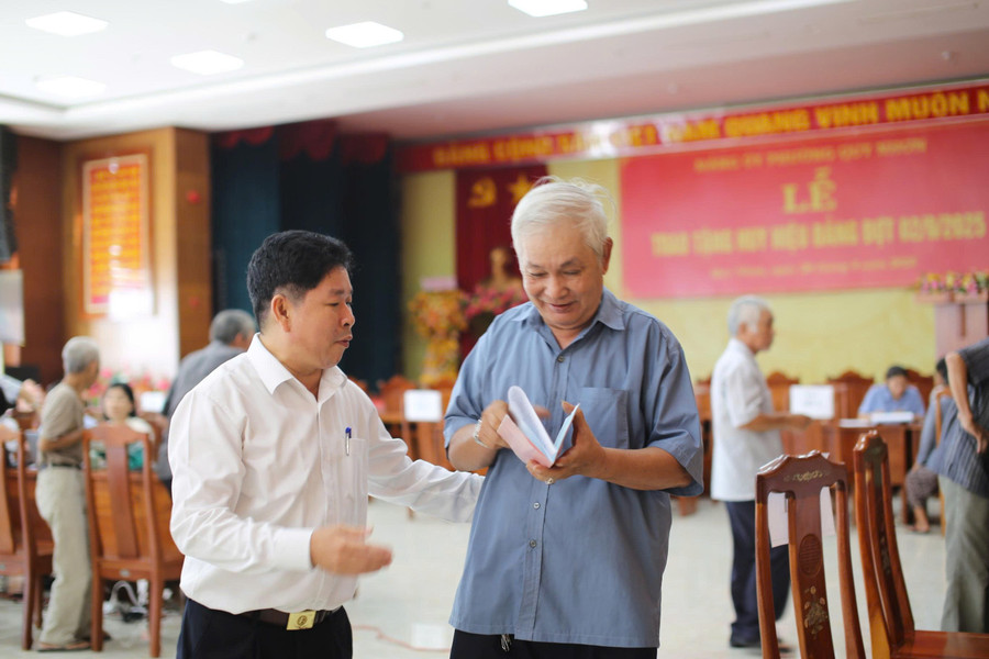 Chủ tịch UBND phường Quy Nhơn Nguyễn Đức Toàn (trái) hướng dẫn người dân làm thủ tục nhận quà. Ảnh: H.P z6967262935568-f5c9f23b00508aa4cd6337b0d0761f2f.jpg