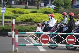 Cậu bé 5 tuổi ra giữa lòng đường để xin tiền người dân đang dừng đèn đỏ. Ảnh: Văn Ngọc