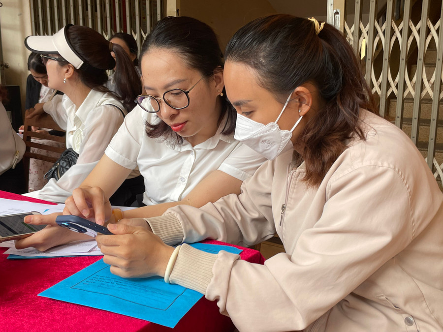 Giáo viên hướng dẫn phụ huynh đăng ký nhập học trực tuyến. Ảnh: Bích Ngọc