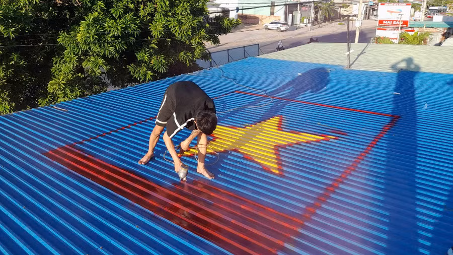 Nhóm bạn trẻ ở huyện Phú Thiện (Gia Lai) cùng nhau vẽ lá cờ Tổ quốc trên mái nhà. Ảnh: NVCC