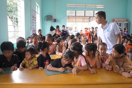 Thầy Lê Văn Bình hướng dẫn em đã biết chữ học tiếng Anh tại lớp học tình thương ở làng Khôi. 