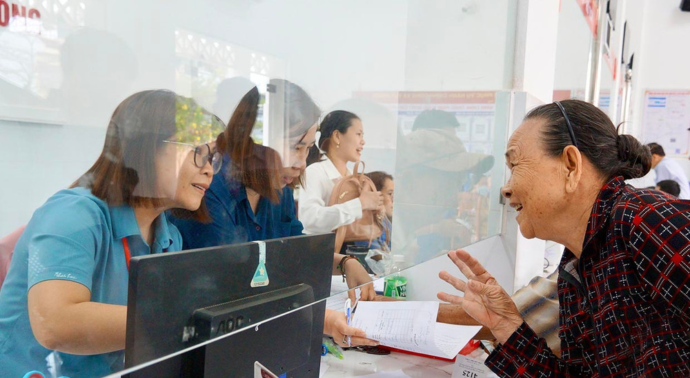 Công chức Văn hóa - Xã hội xã Tuy Phước trao đổi, hướng dẫn người cao tuổi về việc nộp hồ sơ trợ cấp hưu trí. Ảnh: Nguyễn Muội them2.jpg