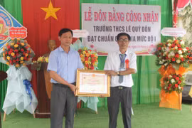 Phó Chủ tịch UBND huyện Krông Pa Nguyễn Tiến Đãng (bìa trái) trao bằng công nhận Trường đạt chuẩn quốc gia mức độ 1. Ảnh: Vũ Chi