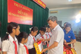 Bí thư Thị ủy Ayun Pa Trần Quốc Khánh tặng quà cho các em học sinh vượt khó vươn lên trong học tập. Ảnh: Vũ Chi