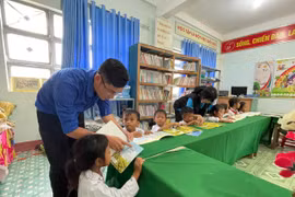 Đoàn thiện nguyện cùng đoàn viên, thanh niên hướng dẫn các em đọc sách được trao tặng từ chương trình Sách về làng tại thư viện nhà trường. Ảnh: Vũ Chi