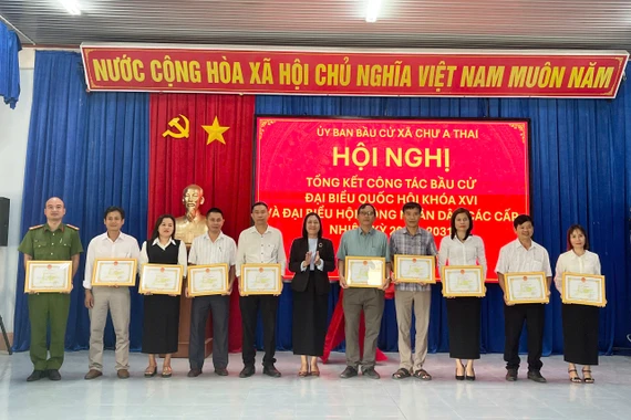 Bí thư Đảng ủy xã Trịnh Thị Hồng (đứng giữa) tặng giấy khen cho các tập thể có thành tích xuất sắc trong công tác bầu cử. Ảnh: Vũ Chi