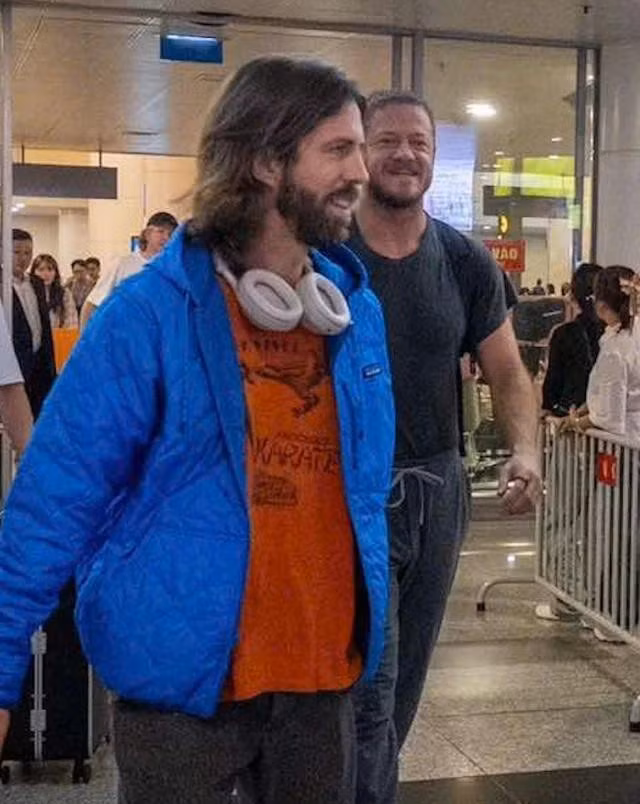 Nghệ sĩ guitar Wayne Sermon và nhóm trưởng Dan Reynolds giản dị, tươi cười tại sân bay