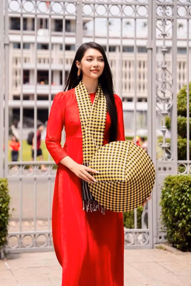 Áo dài đỏ phối khăn và nón họa tiết khăn rằn đến từ thương hiệu KHANRAN của stylist Thịnh Chocolate là một gợi ý cho quý cô trong mùa lễ. Khi diện bộ trang phục này xuống phố, Hoa hậu Đại dương Thu Uyên khéo léo phối cùng hoa tai tròn, tóc dài thẳng và giày cao gót tông trắng nổi bật