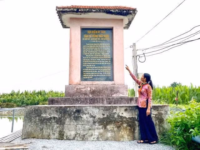Bà Đỗ Thị Tiến bên bia di tích Căn cứ rừng dừa nước (xã Tịnh Khê, TP.Quảng Ngãi)