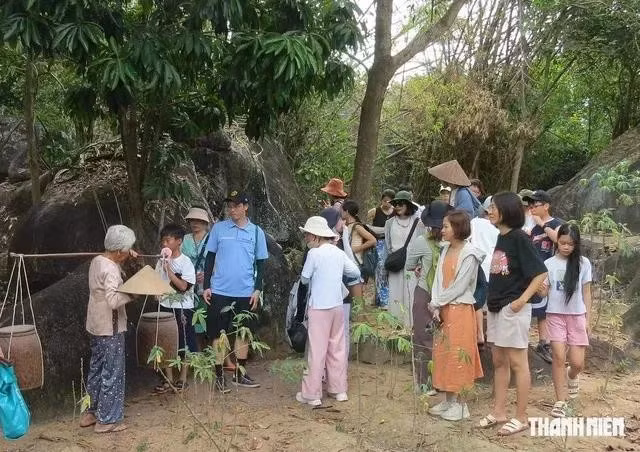 Du khách nghe chuyện gánh mắm đổi lúa do cụ Trần Thị Chín (người đang gánh mắm) kể lại