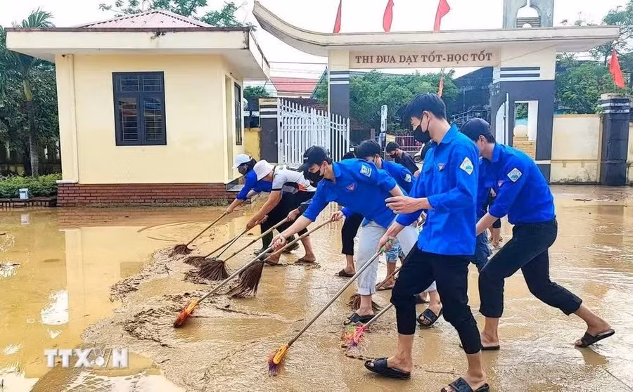 Các đoàn viên thanh niên dọn dẹp vệ sinh, cào đẩy bùn non... giúp các điểm trường bị ảnh hưởng nặng trên địa bàn huyện Quảng Ninh, tỉnh Quảng Bình. (Ảnh: TTXVN)