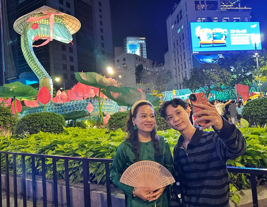 Chị Ngọc Thảo (40 tuổi) và anh Tấn Thông (33 tuổi) đi từ Q.4 đến Q.1 để tham quan đường hoa đêm giao thừa. "Lát tôi còn về nhà cúng giao thừa, nên đến đây chủ yếu để tham quan đường hoa. Năm nay, linh vật rắn đẹp quá luôn, hoa đẹp nhưng ấn tượng nhất với tôi là tạo hình rắn dễ thương", chị chia sẻ