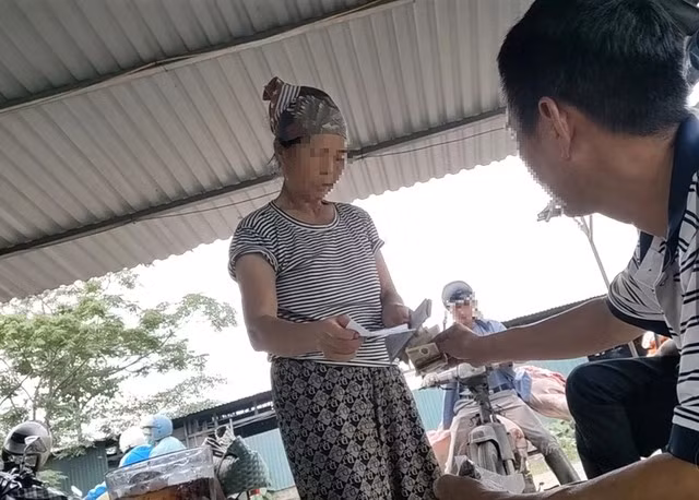 Bà M. phát biên lai thu phí giết mổ cho thương lái. Ảnh: Tuấn Minh - Đình Huy