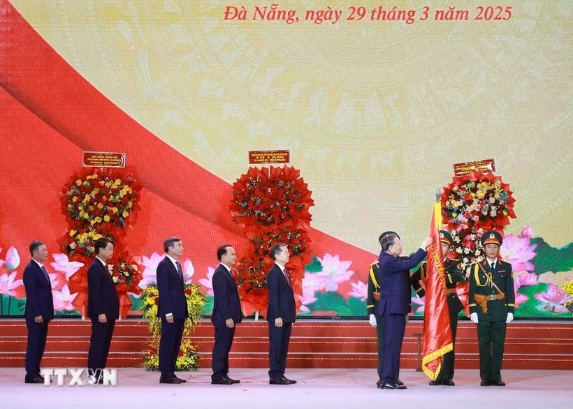 Tổng Bí thư Tô Lâm gắn Huân chương Lao động hạng Nhất lên Cờ truyền thống của Thành phố Đà Nẵng. (Ảnh: Thống Nhất/TTXVN)