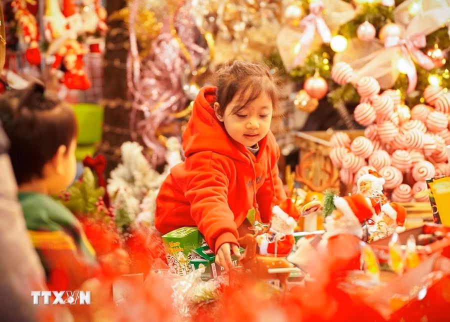 Một bé gái lựa chọn cho mình món đồ chơi Giáng sinh trên phố Hàng Mã, Hà Nội. (Ảnh: Khánh Hòa/TTXVN)