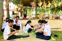 Các em học sinh trải nghiệm đan gùi với nghệ nhân làng Ngơm Thung, xã Ia Pết, huyện Đak Đoa. Ảnh: L.N