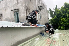 Cán bộ, chiến sĩ Trung đoàn Cảnh sát cơ động Nam Trung Bộ giúp người dân phường Quy Nhơn Tây chằng chống nhà cửa, ứng phó bão số 13.